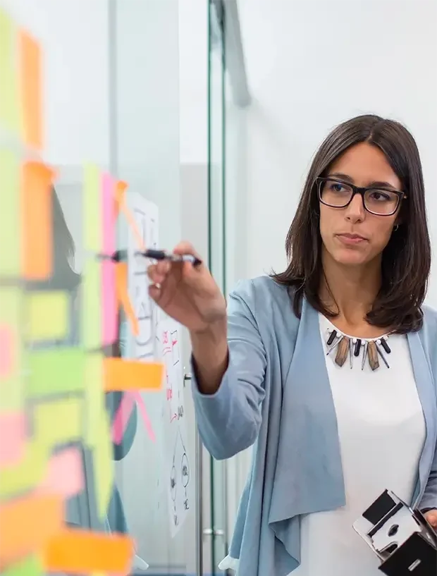 Woman in glasses pointing to a diagram with a pen